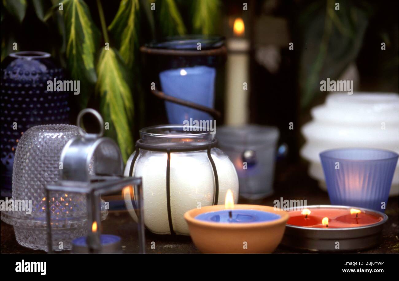 Collection of candles and candle holders in evening light - Stock Photo