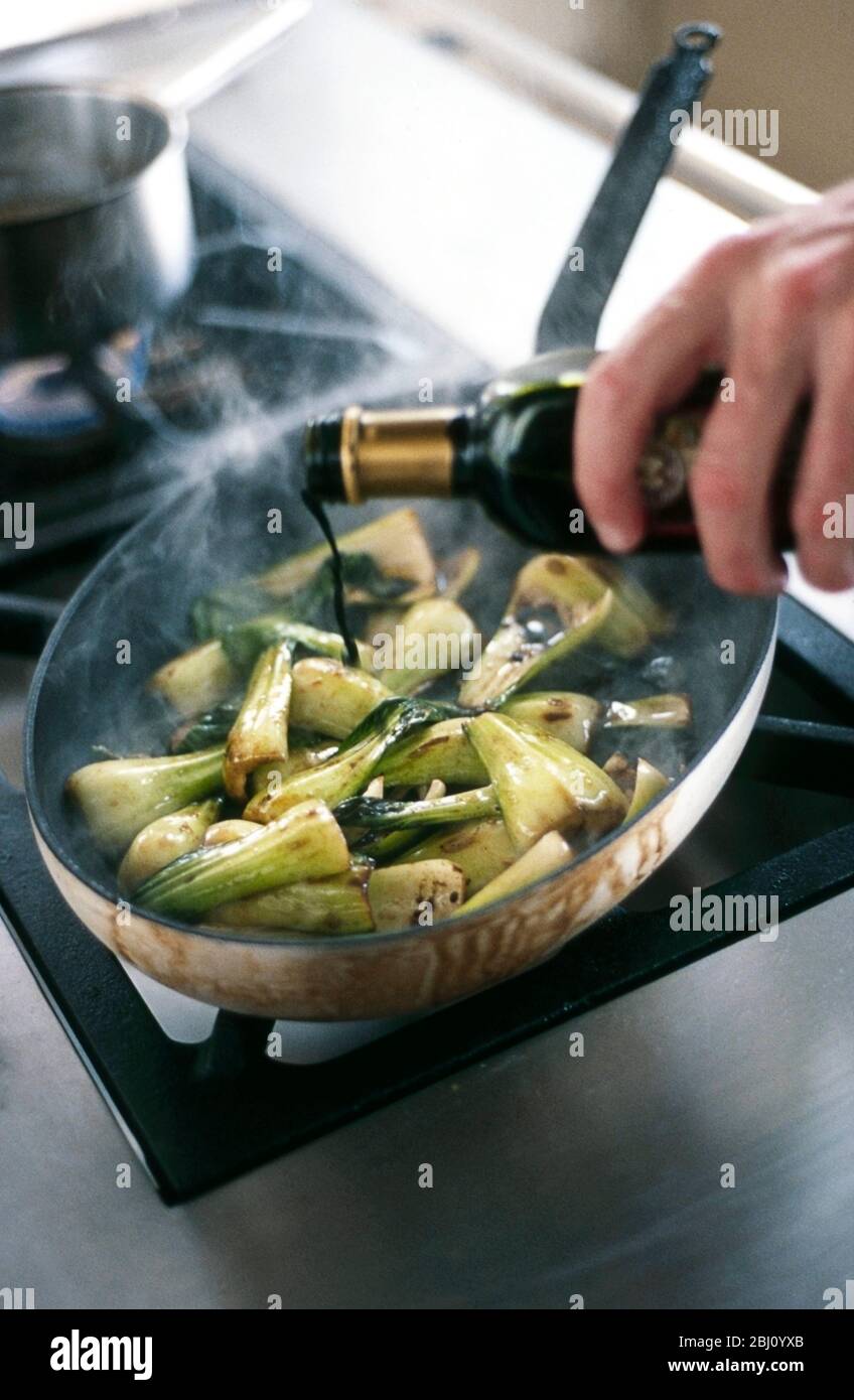 Cooking pakchoi in hot sesame oil and sprinkled with soy sauce - Stock Photo