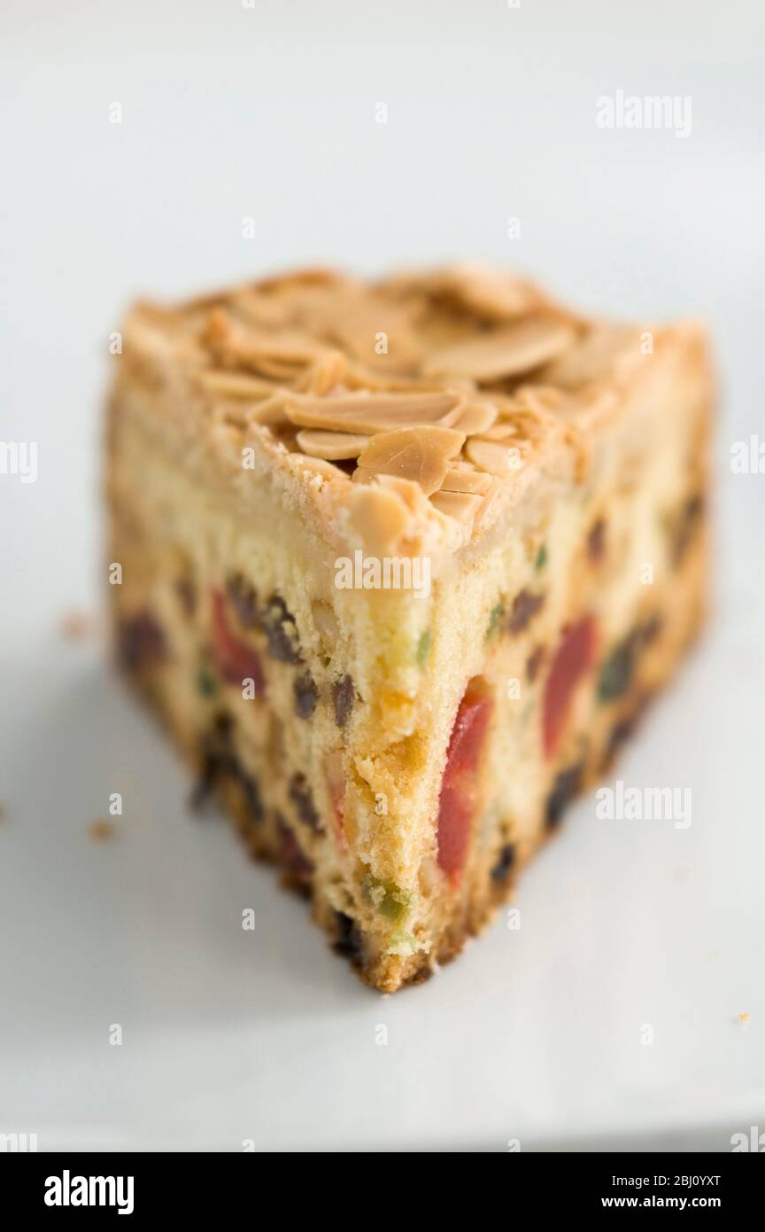 Slice of light fruitcake with sultanas, candied peel and glace cherries - Stock Photo