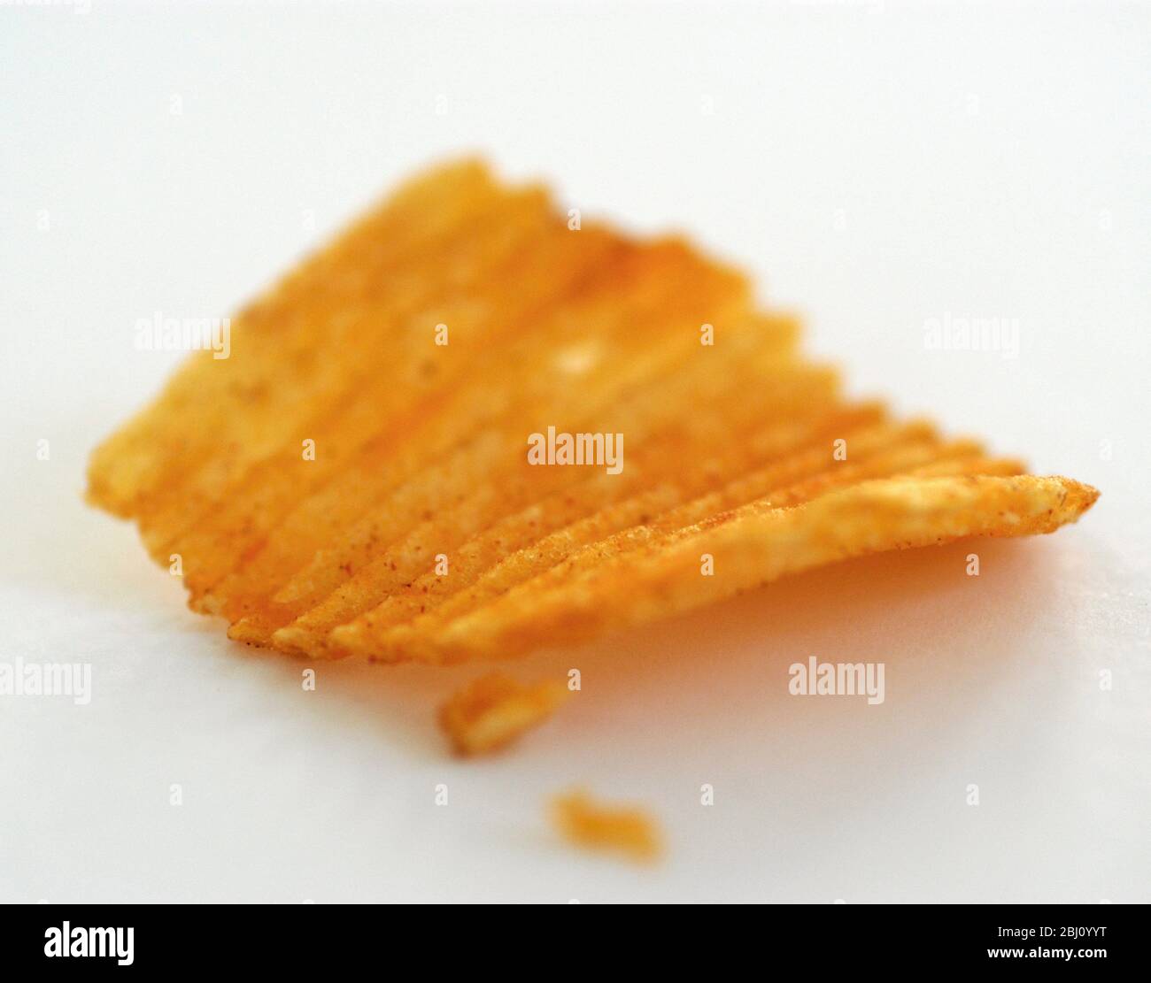 Crinkled potato crisps on white background. Very short depth of field - Stock Photo