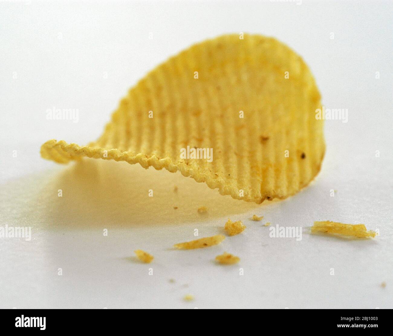 Single groovy potato crisp on white background - Stock Photo