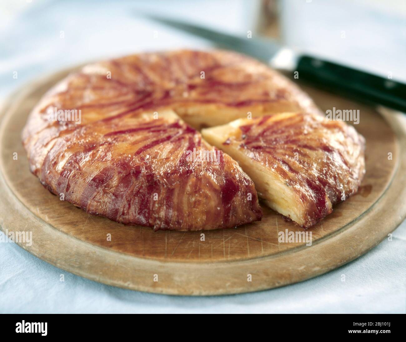 Carefully sliced potatoes layered with melted butter cooked in a saute pan lined with thinly sliced bacon, wrapped round on to the top (while it is co Stock Photo