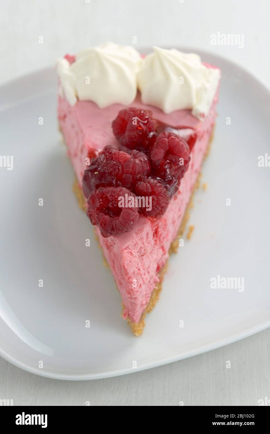 Slice of delicious raspberry mousse cake, on white plate - Stock Photo