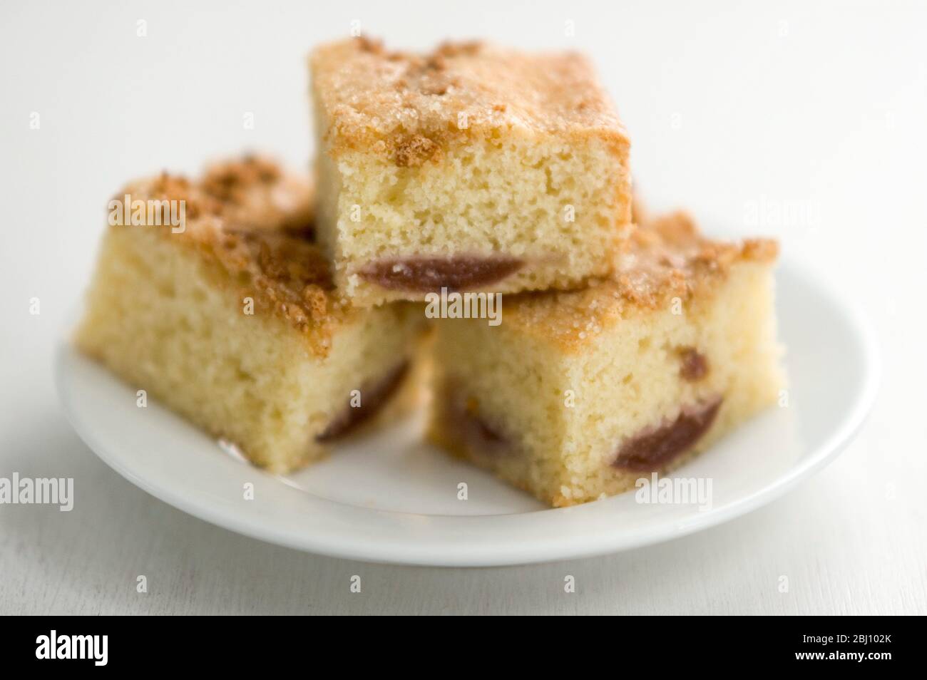 Three squares of fig and sesame cake on white plate - Stock Photo
