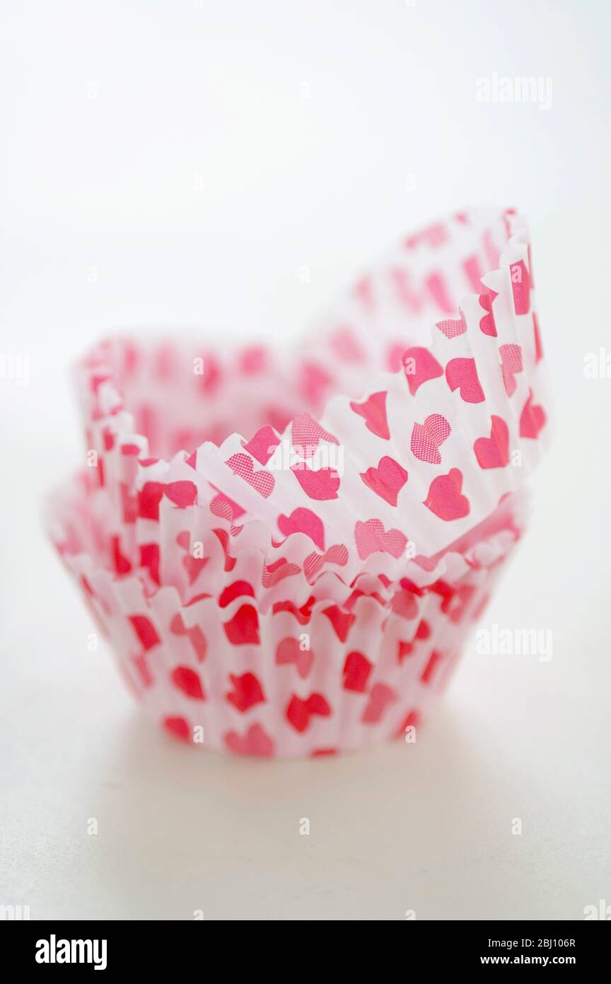 Paper cases for making muffins and fairy cakes - decorated with small red hearts - Stock Photo