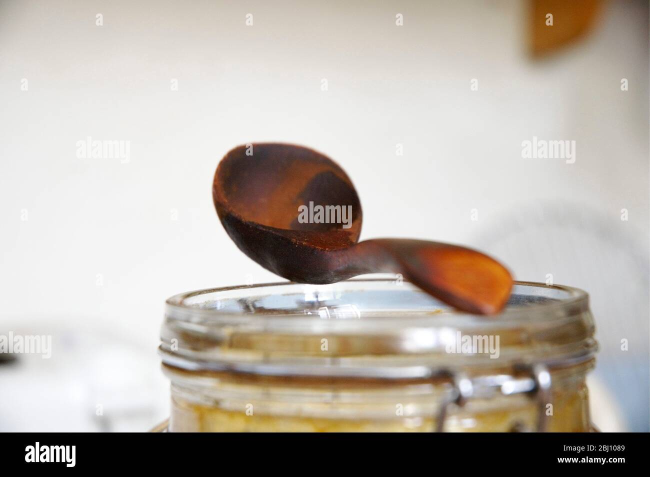 Well worn wooden coffee measure balanced on top of jar used for storing coffee - Stock Photo