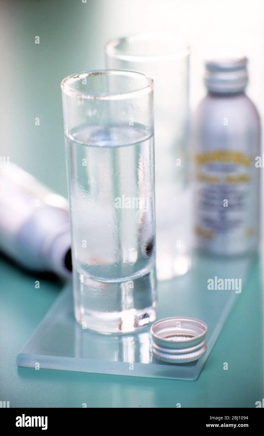 Two shot glasses of icy vodka with bottles nearby - Stock Photo