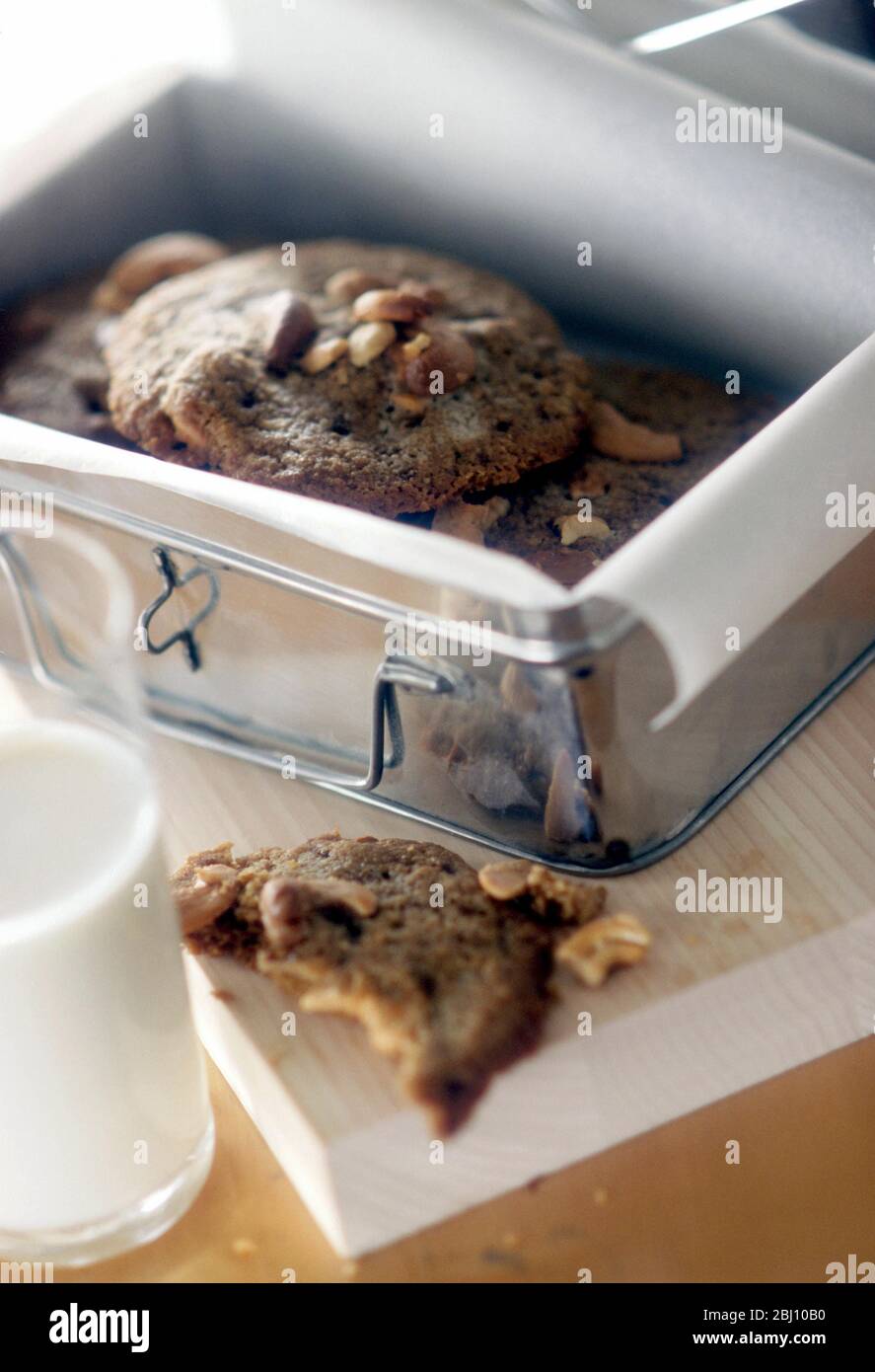 Chocolate nut cookies in paper lined storage tin - Stock Photo