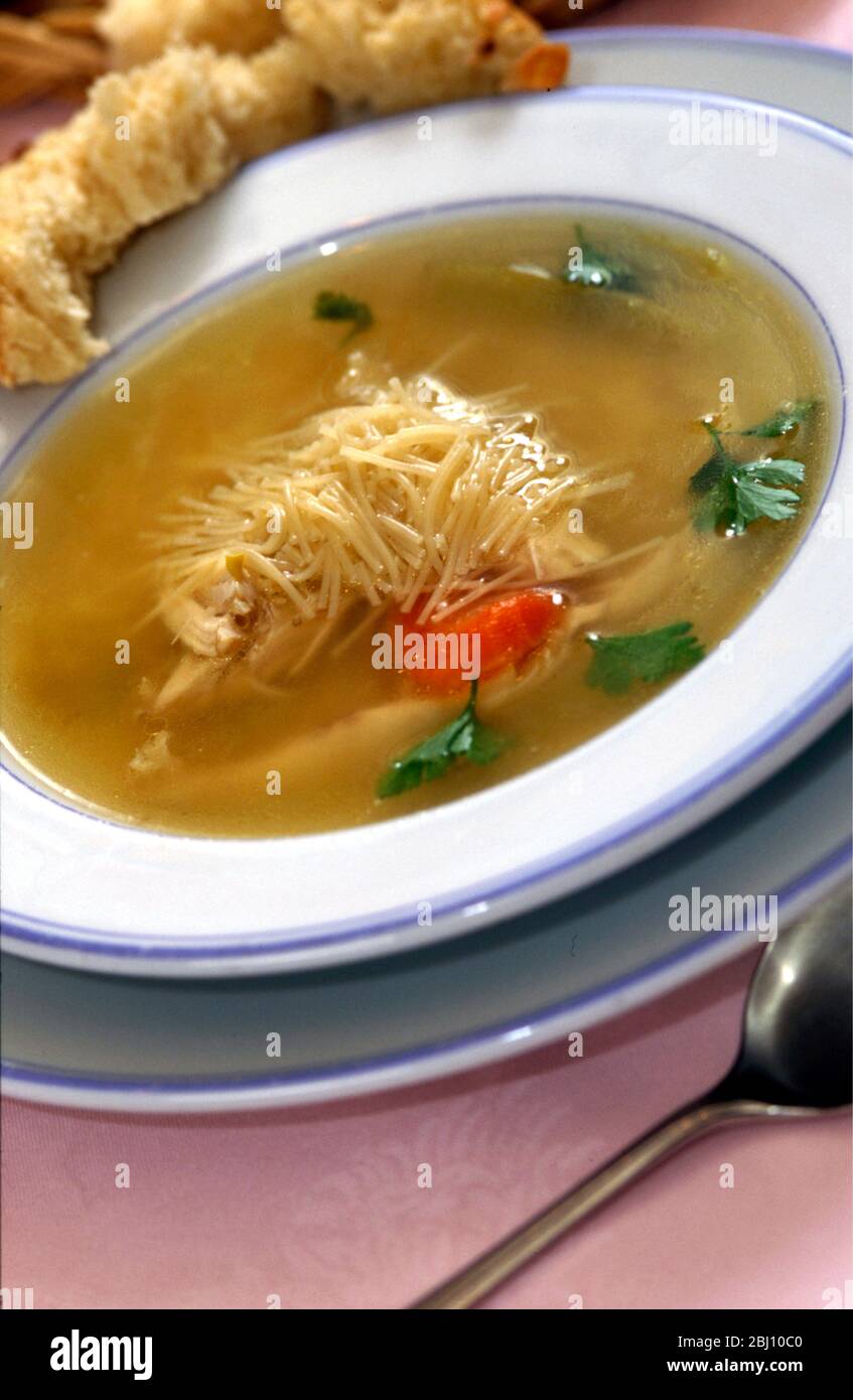 bowl of homemade chicken noodle soup with chunk of crusty bread - Stock Photo