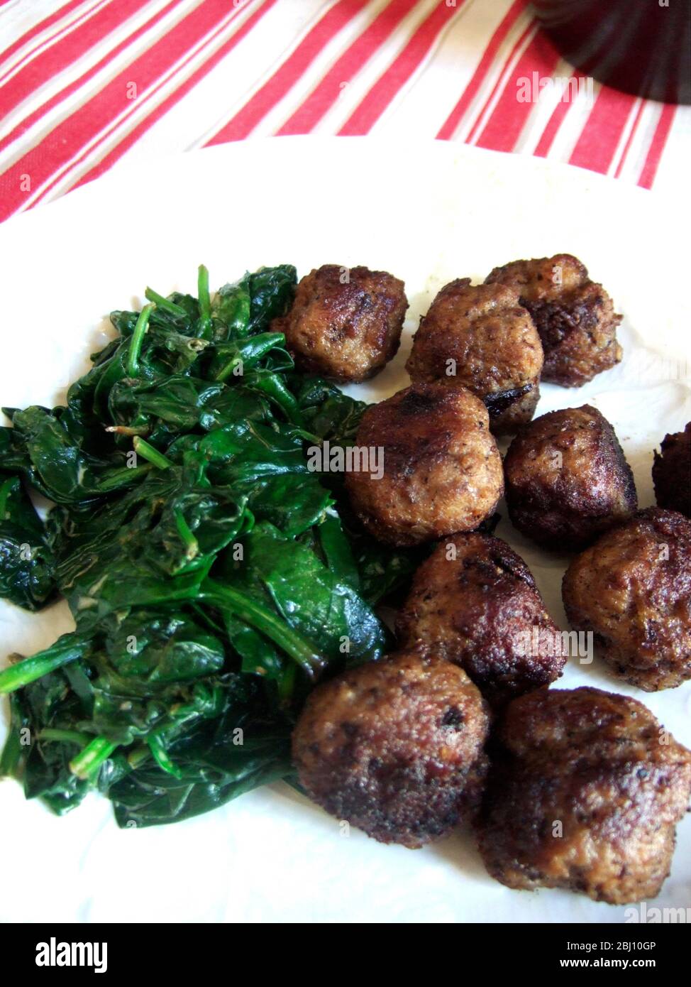 Swedish meatballsmade of pork and beef, with wilted spinach - Stock Photo