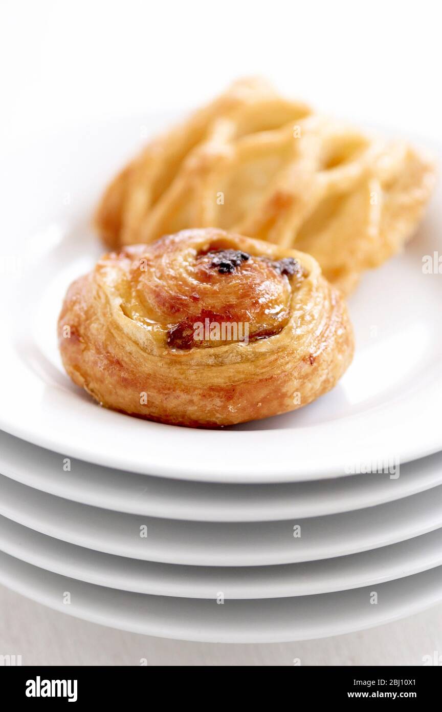 Small danish pastries on stack of white plates - Stock Photo
