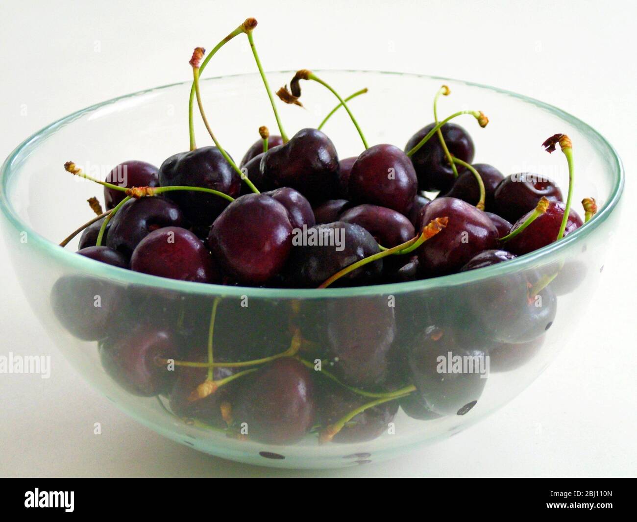 Glass bowl of dark red cherries - Stock Photo