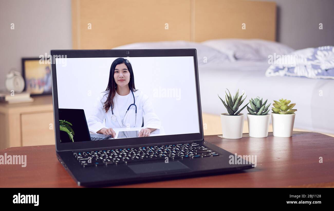 Asian doctor provide health consultation services through website for online consultation via laptop computer, about illness and medication via video Stock Photo