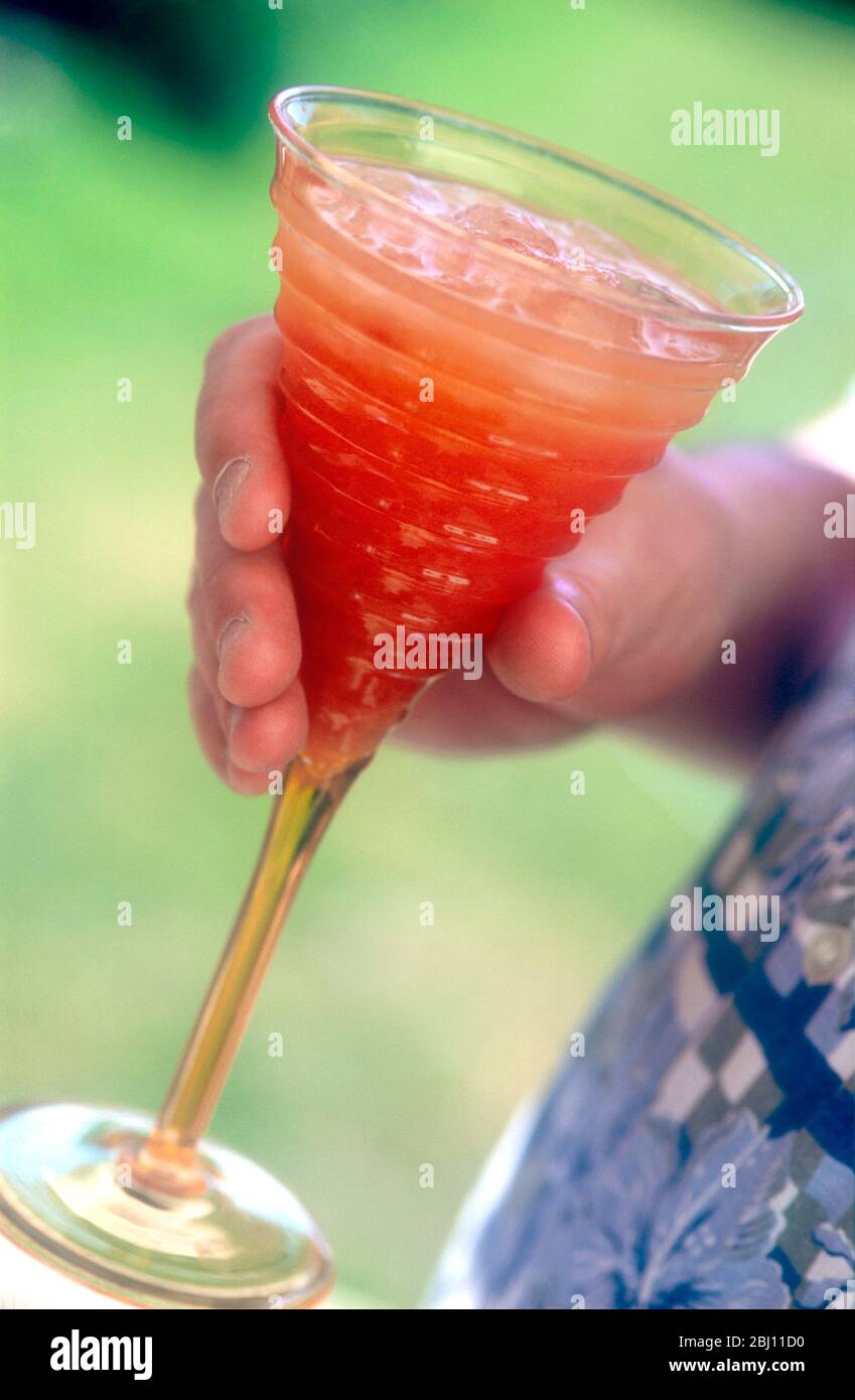 Cocktail glass of fresh fruit drink held in hand - Stock Photo