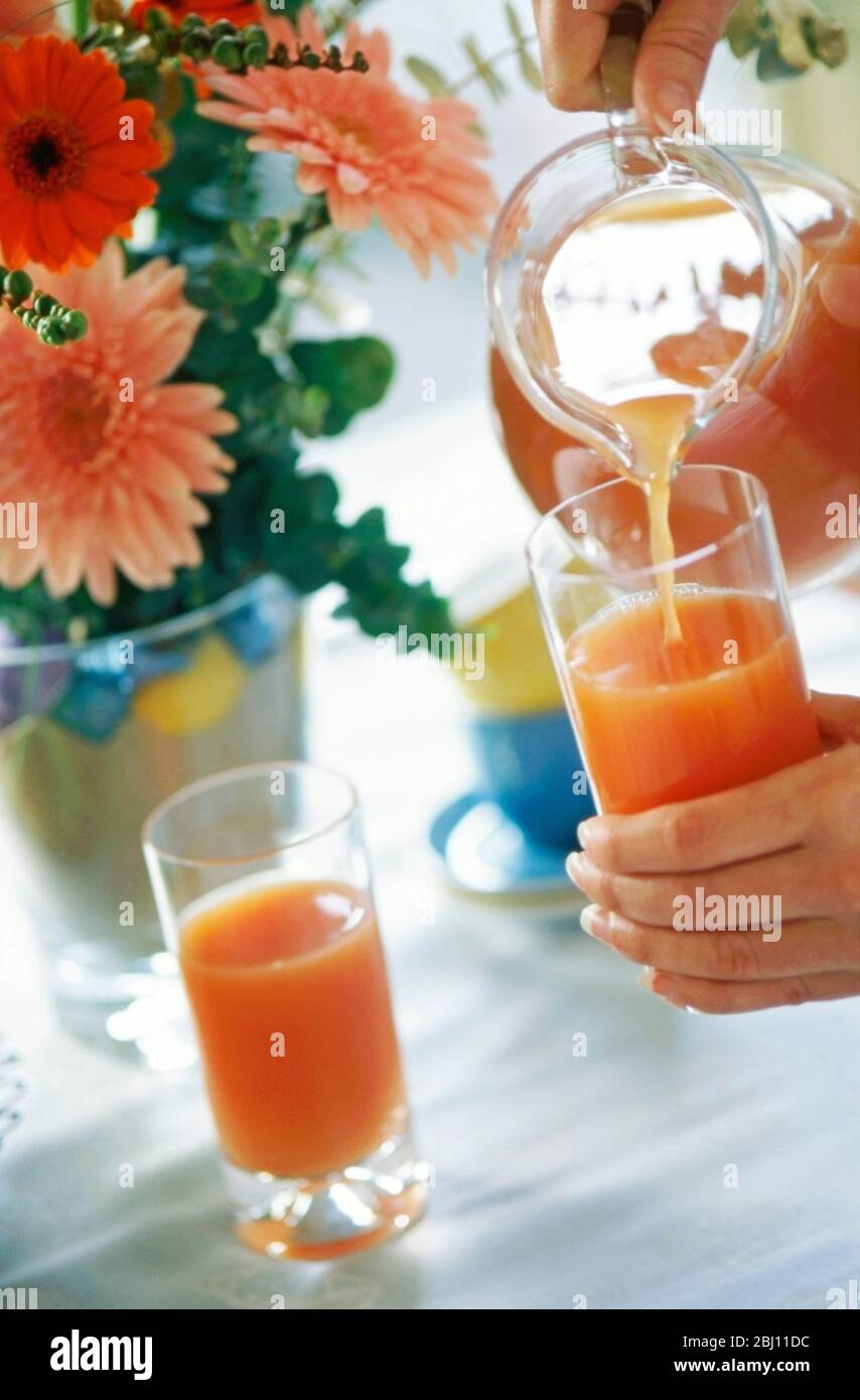 Pink fruit juice or smoothie being poured into tall hi-ball glasses - Stock Photo