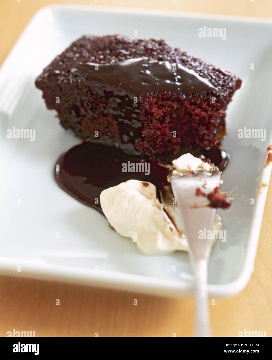 Chocolate sponge pudding with sticky sauce and cream - Stock Photo