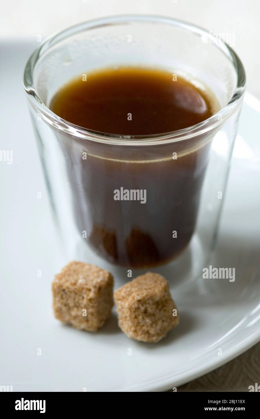Bodum coffee glass with espresso coffee sugar lump and spoon on linen cloth - Stock Photo
