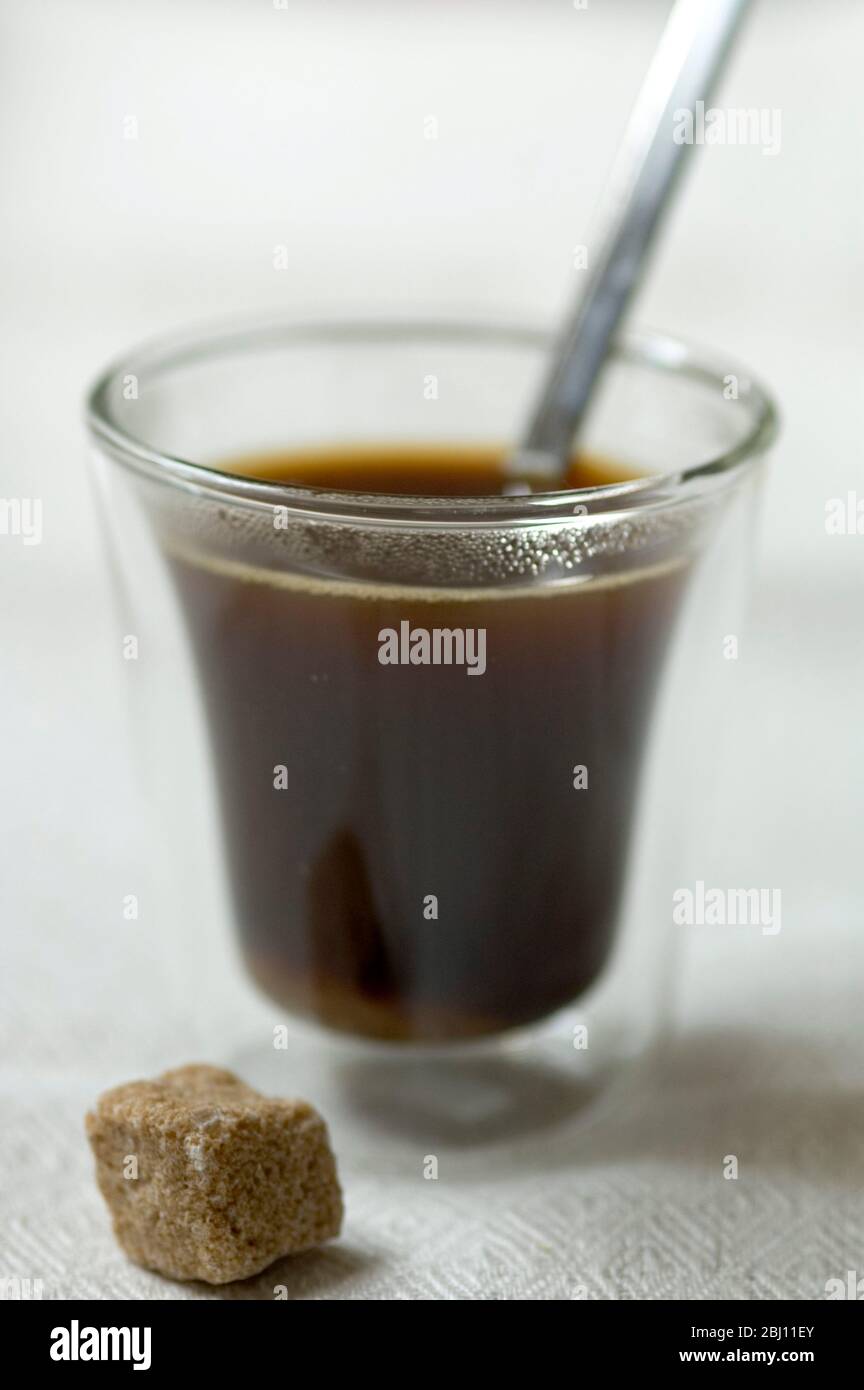 Bodum coffee glass with espresso coffee sugar lump and spoon on linen cloth - Stock Photo