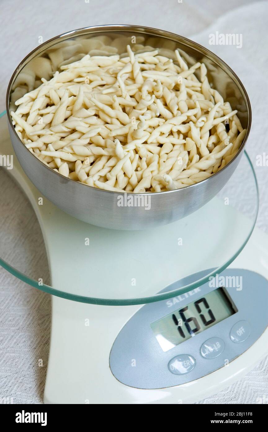 Weighing pasta to control portion sizes - Stock Photo