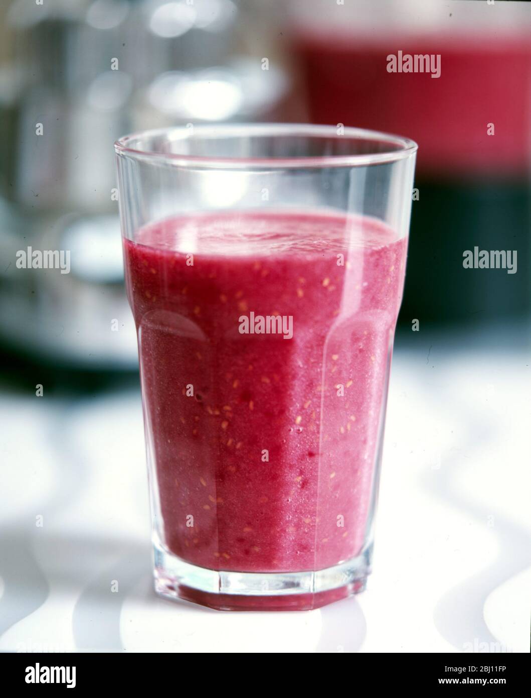Chunky glass of pureed raspberry smoothie - - Stock Photo