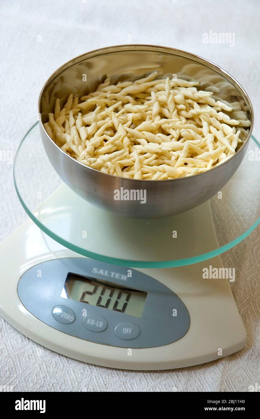 Weighing pasta to control portion sizes - Stock Photo