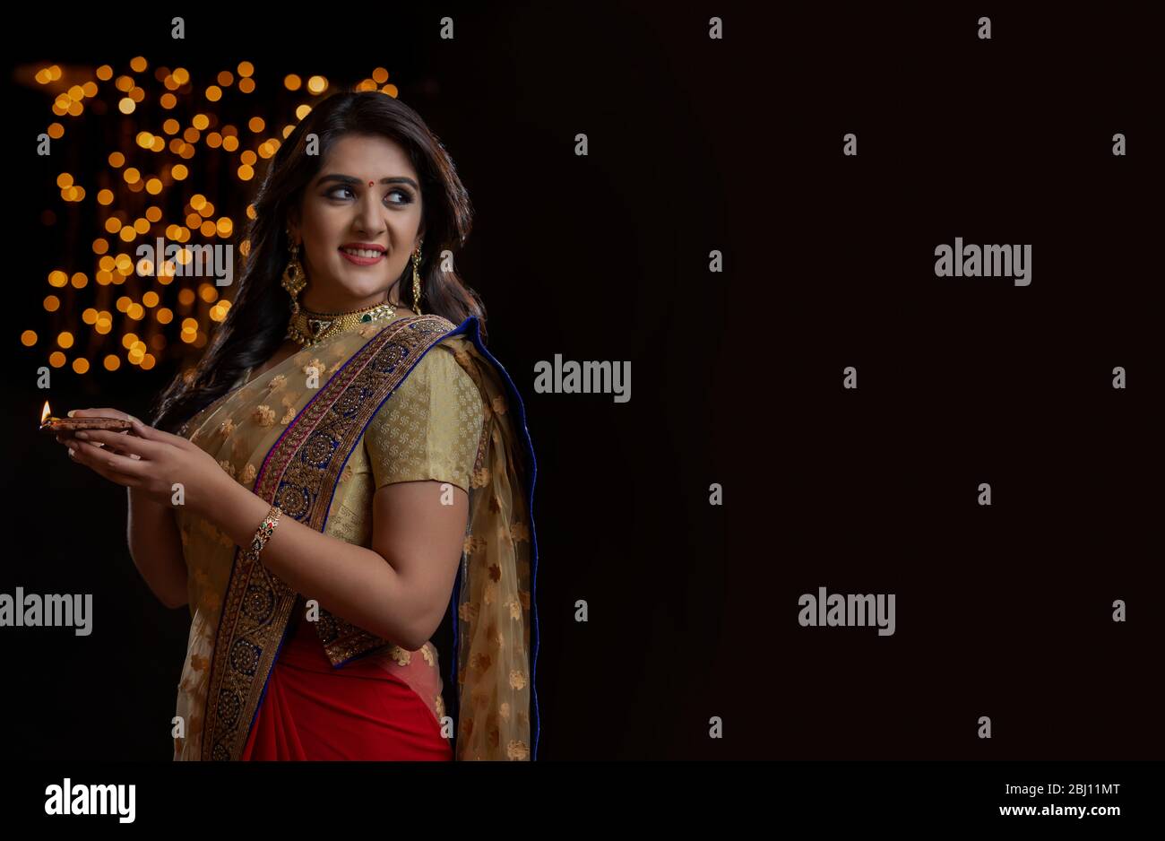 woman in  saree holding diya and smiling Stock Photo