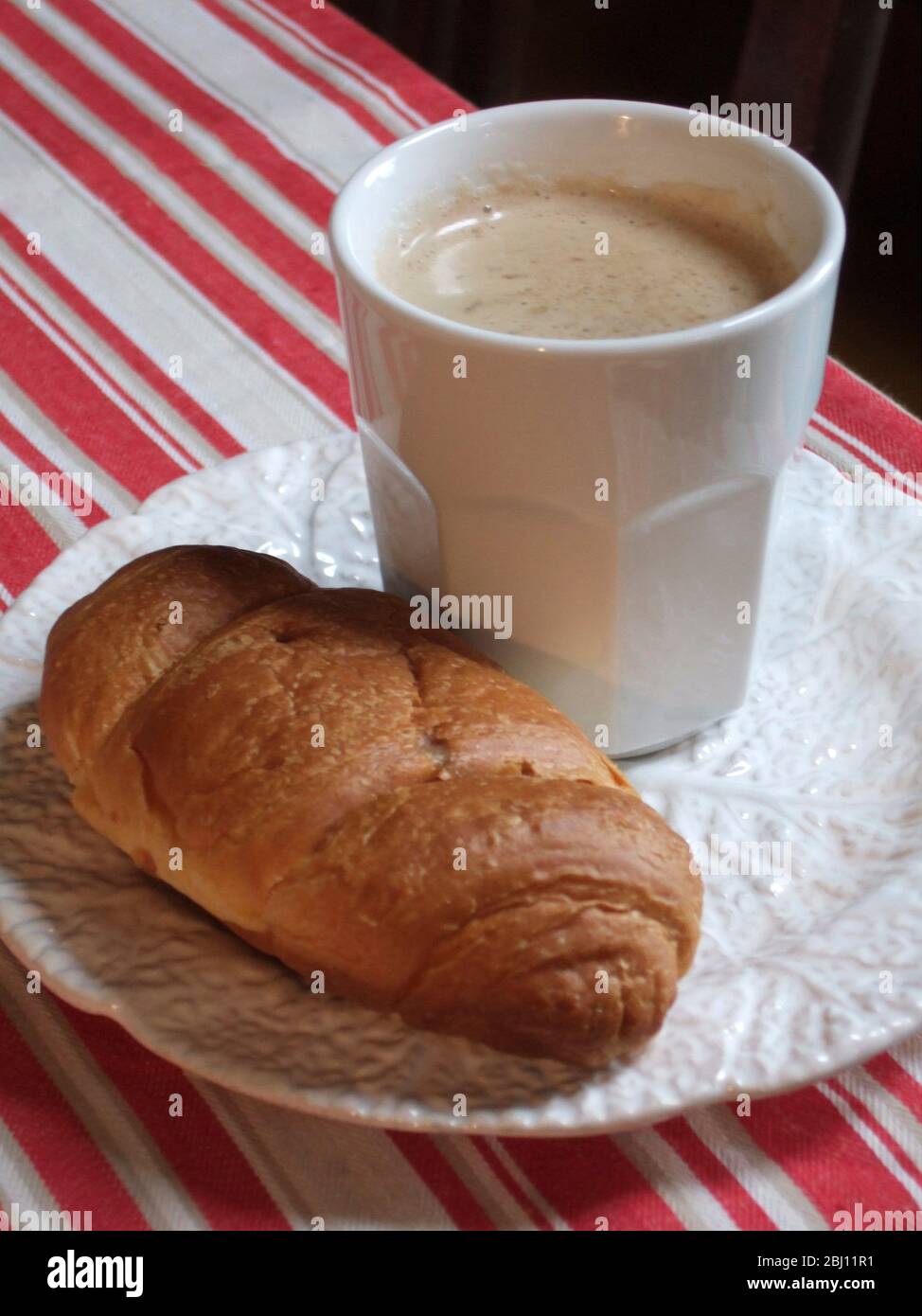 White mug of coffee on plate with croissant - Stock Photo