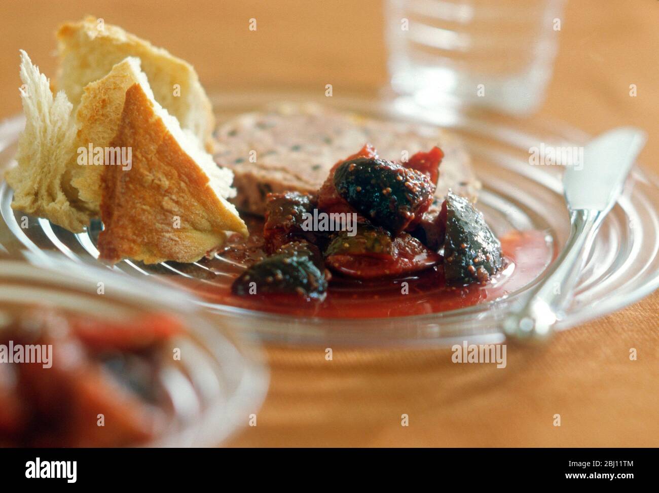 Starter or light meal of fig conserve with slice of terrine and crusty bread - Stock Photo