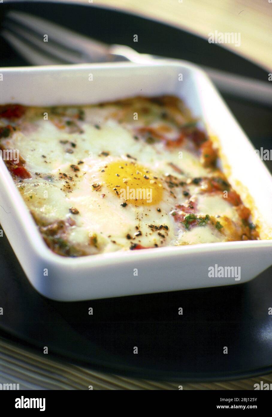 Baked egg with peppers and onions in square dish - - - Stock Photo