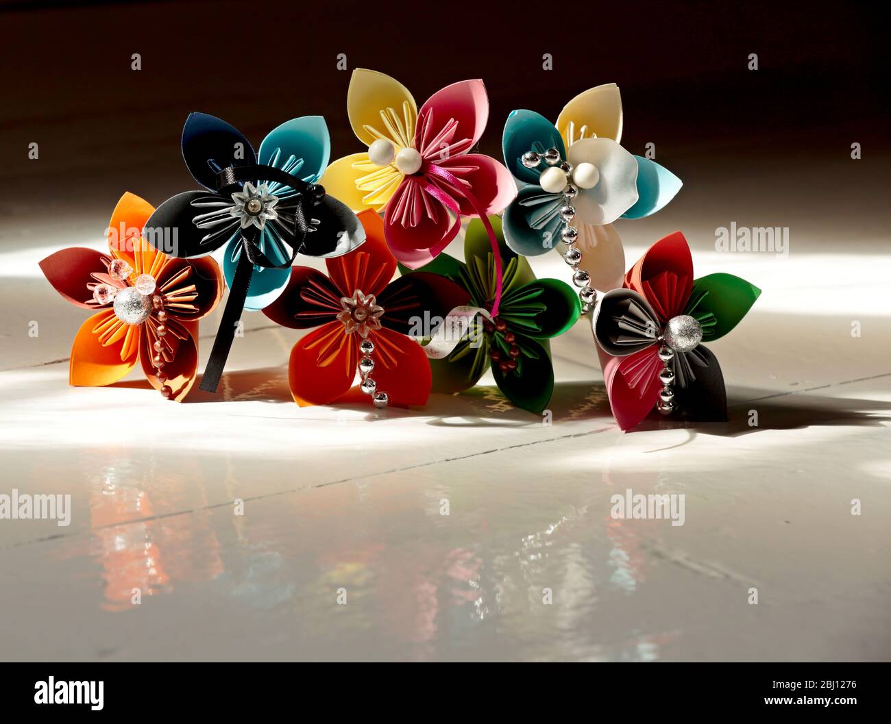Beautiful self made origami flowers on a white shiny floor in light from a window Stock Photo