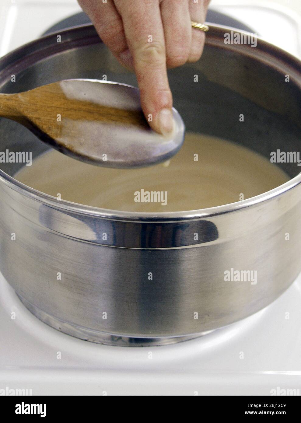 Making custard and checking how far it has thickened - Stock Photo