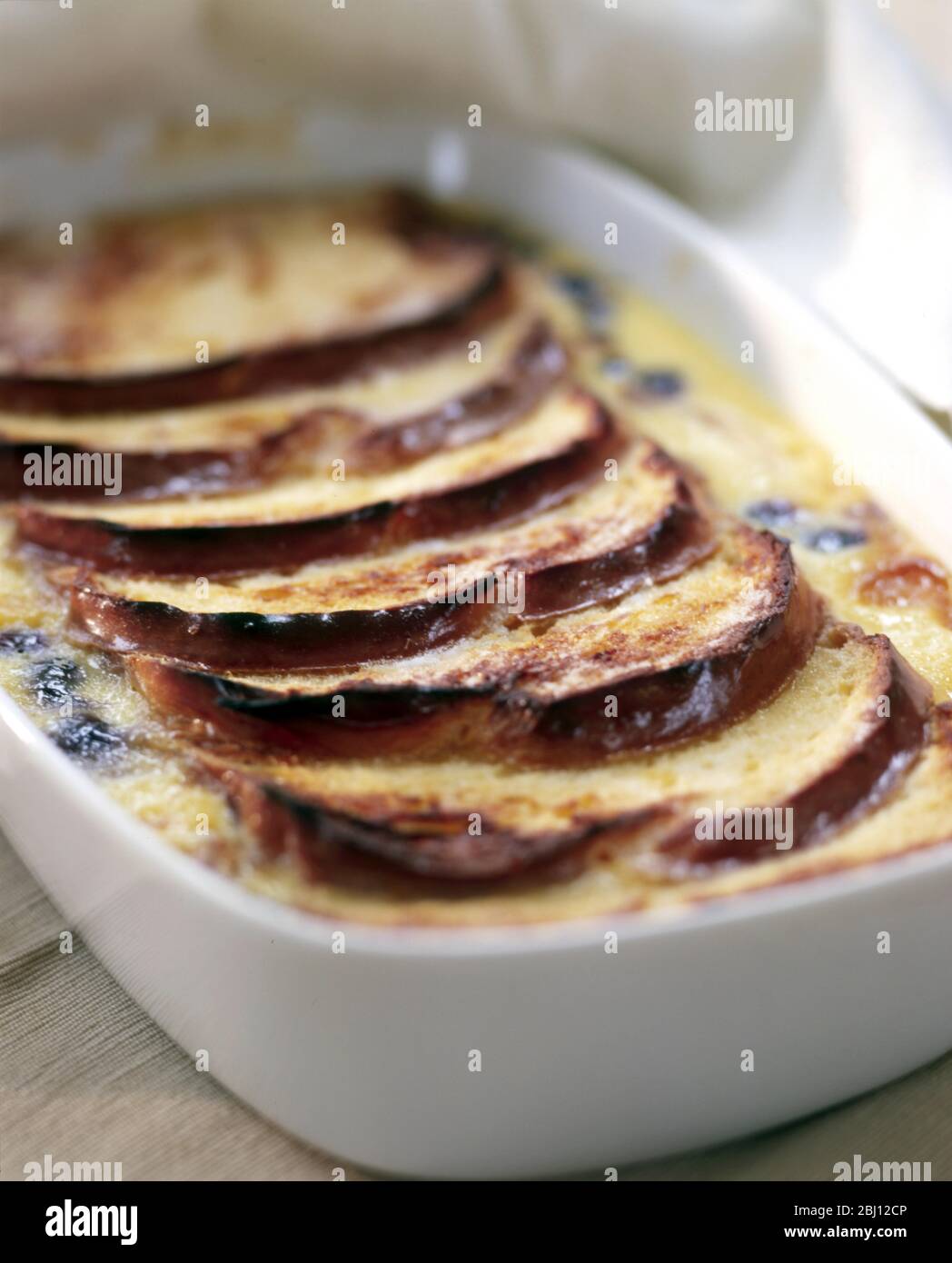 Classic bread and butter pudding in white ovenproof dish - Stock Photo