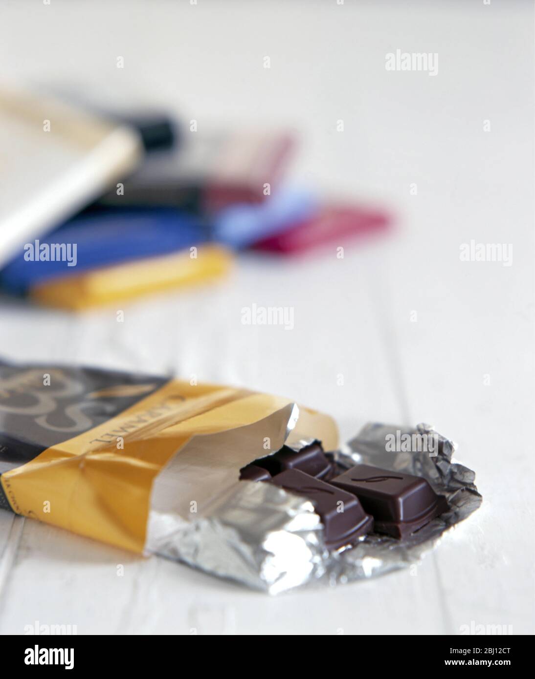 Selection of chocolate bars with one in front open showing dark plain chocolate - Stock Photo