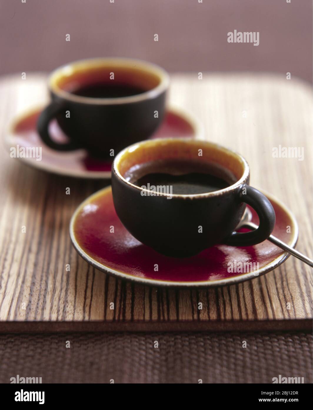 Two attractive modern pottery cups of espresso coffee - Stock Photo