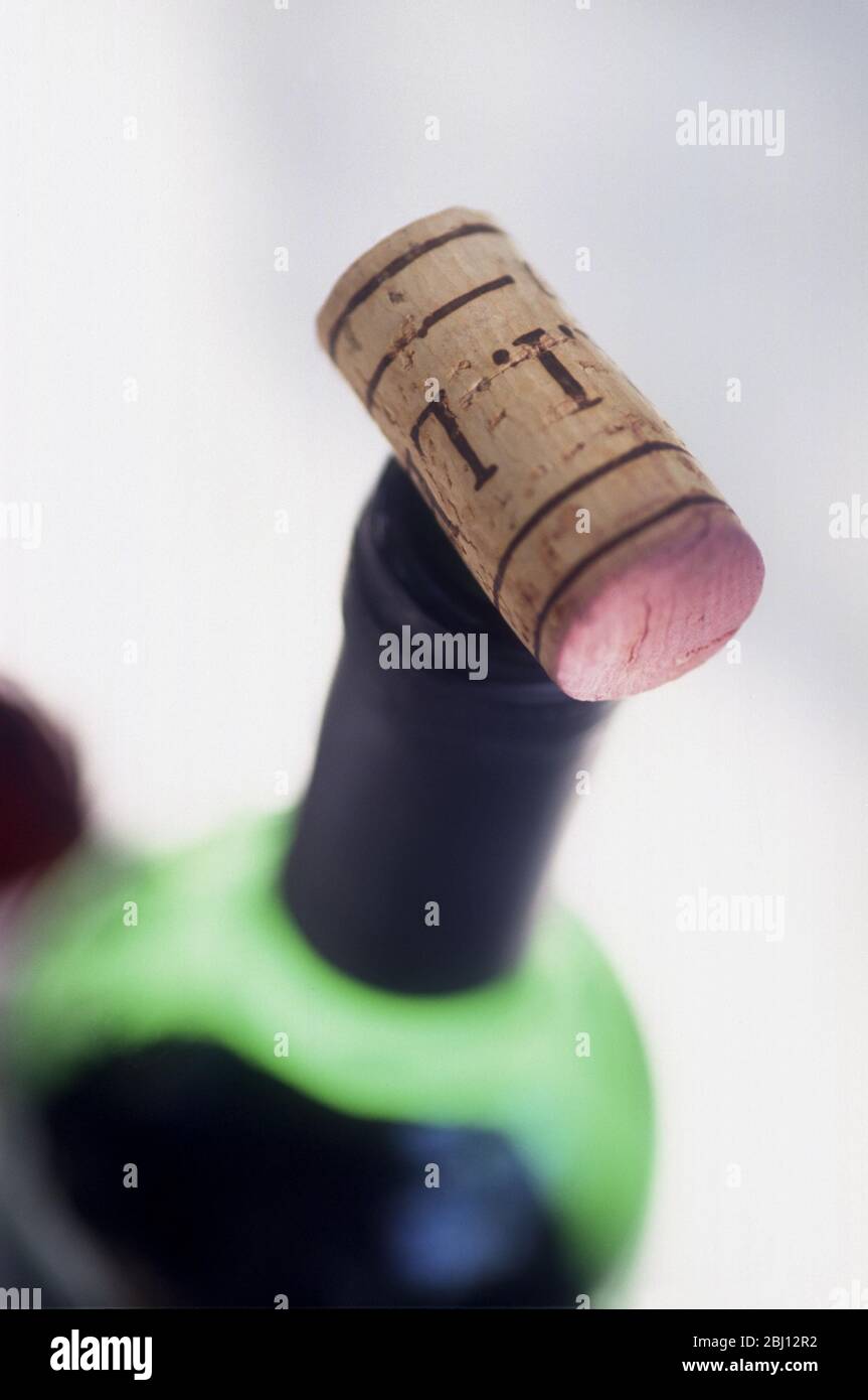 Bottle of claret breathing after opening with cork balanced on lip - Stock Photo