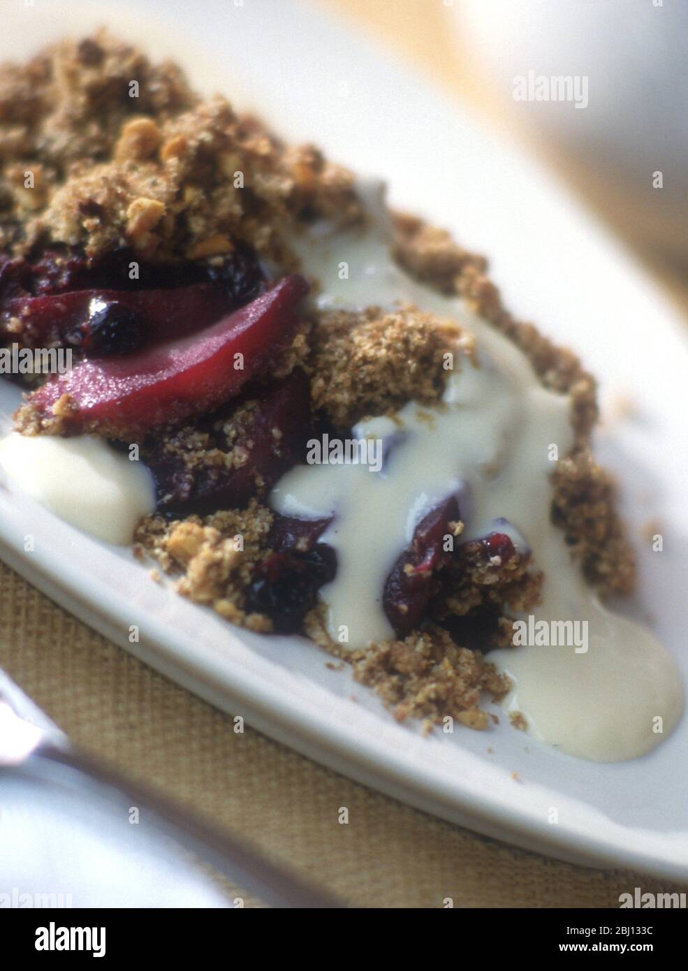 Apple and blackcurrant crumble with cream - Stock Photo