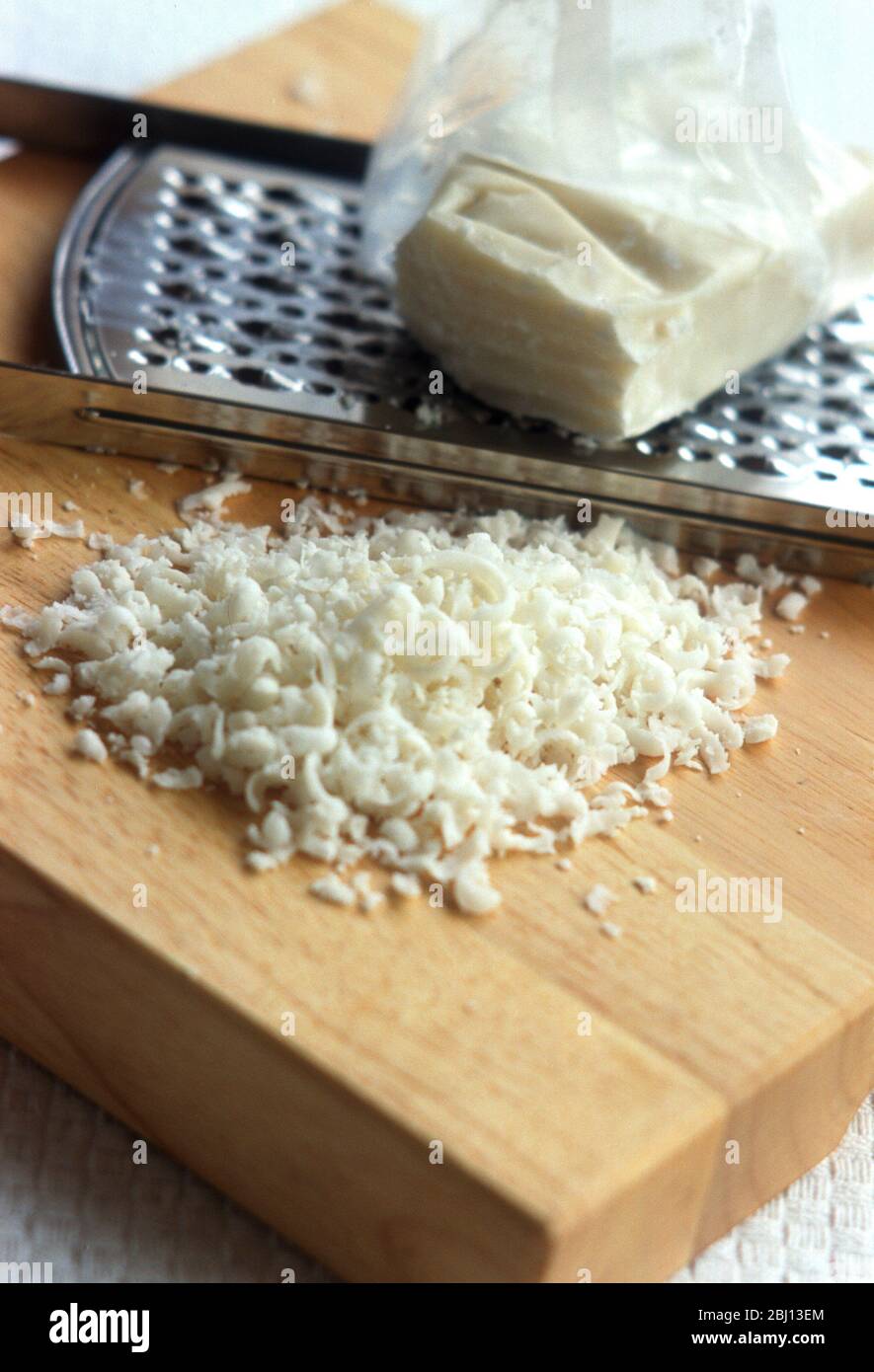 Grating creamed coconut - Stock Photo