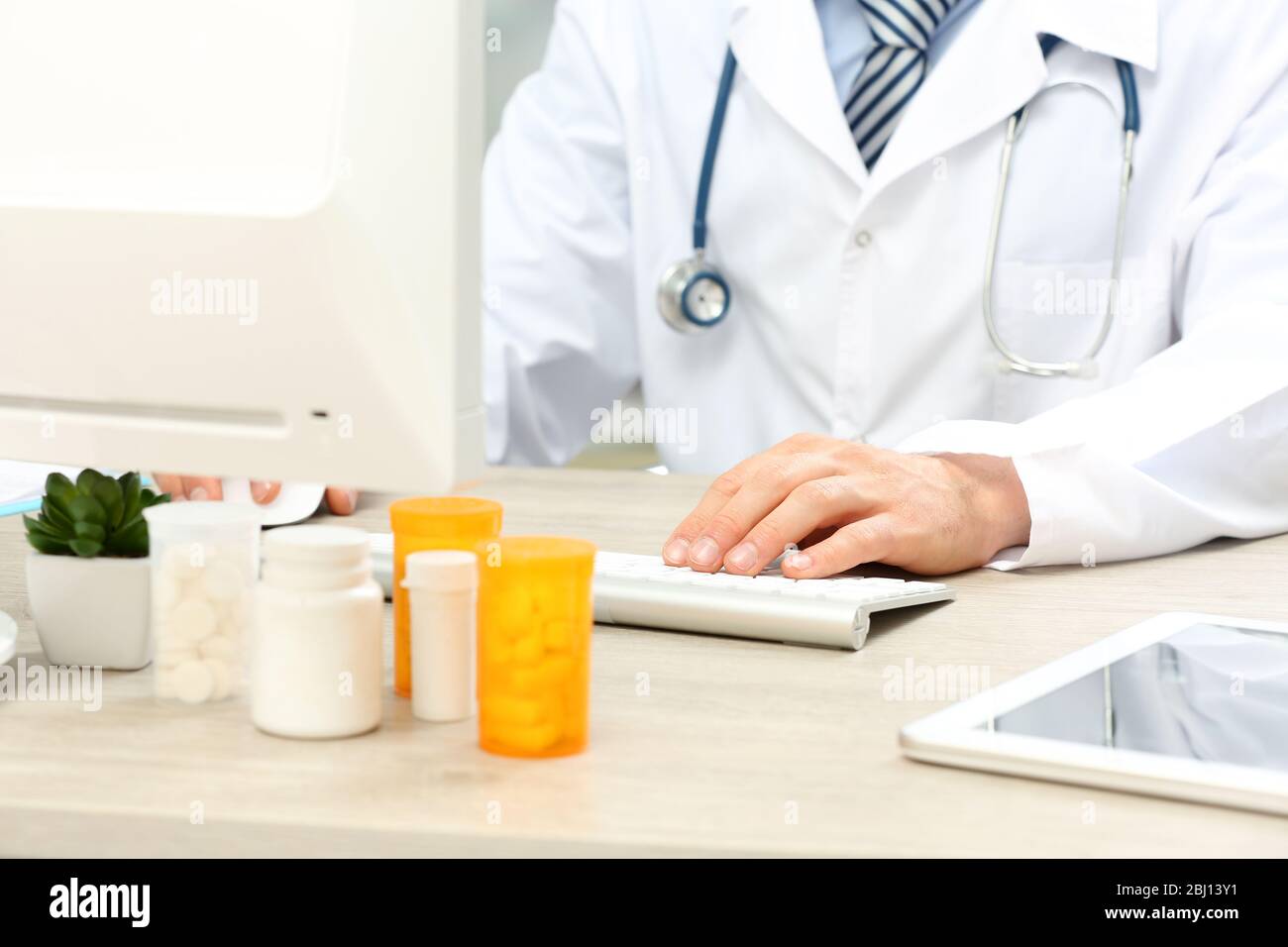 Doctor working at table in office Stock Photo - Alamy