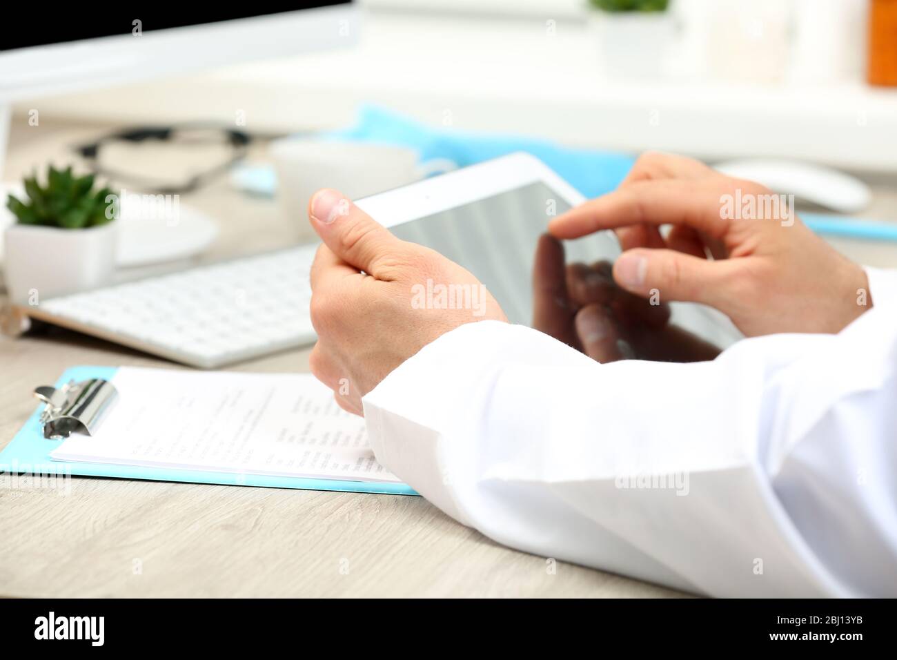 Doctor working at table in office Stock Photo - Alamy
