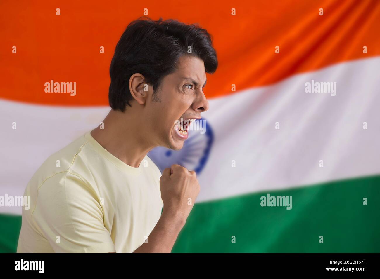 young man cheering with a clenched fist standing infront of indian flag, independence day Stock Photo