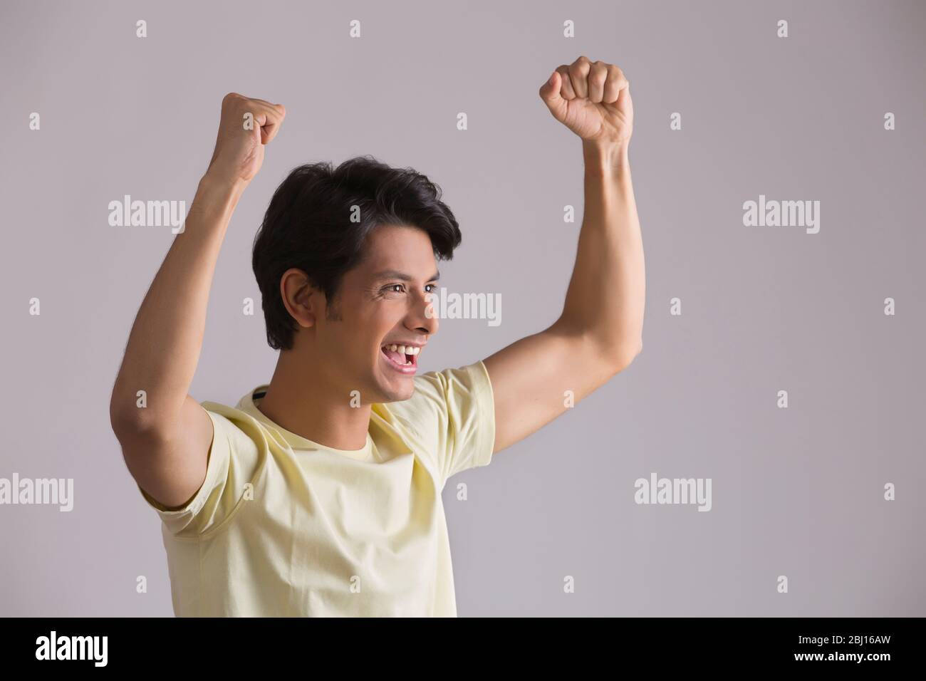 young man cheering by raising hands up Stock Photo