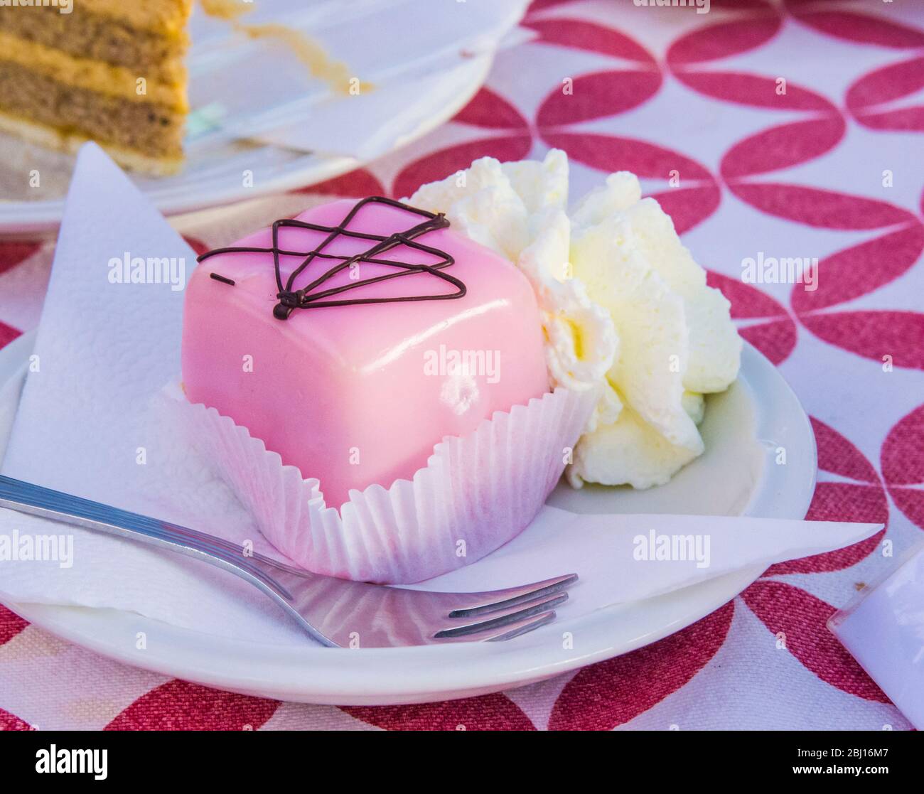 single-twist vanilla and chocolate sponge cakes covered with strawberry icing served with whipped cream Stock Photo