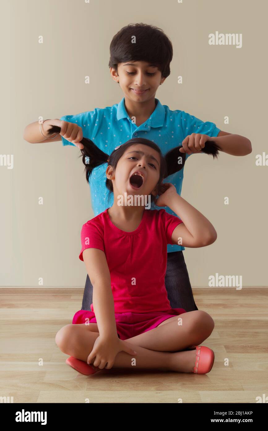 brother teasing his sister by pulling her hair Stock Photo - Alamy
