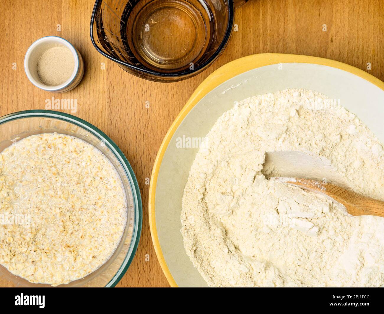 Mixing oat flour with strong white bread flour while soaking oats in oat milk with yeast and water for making oat bread Stock Photo