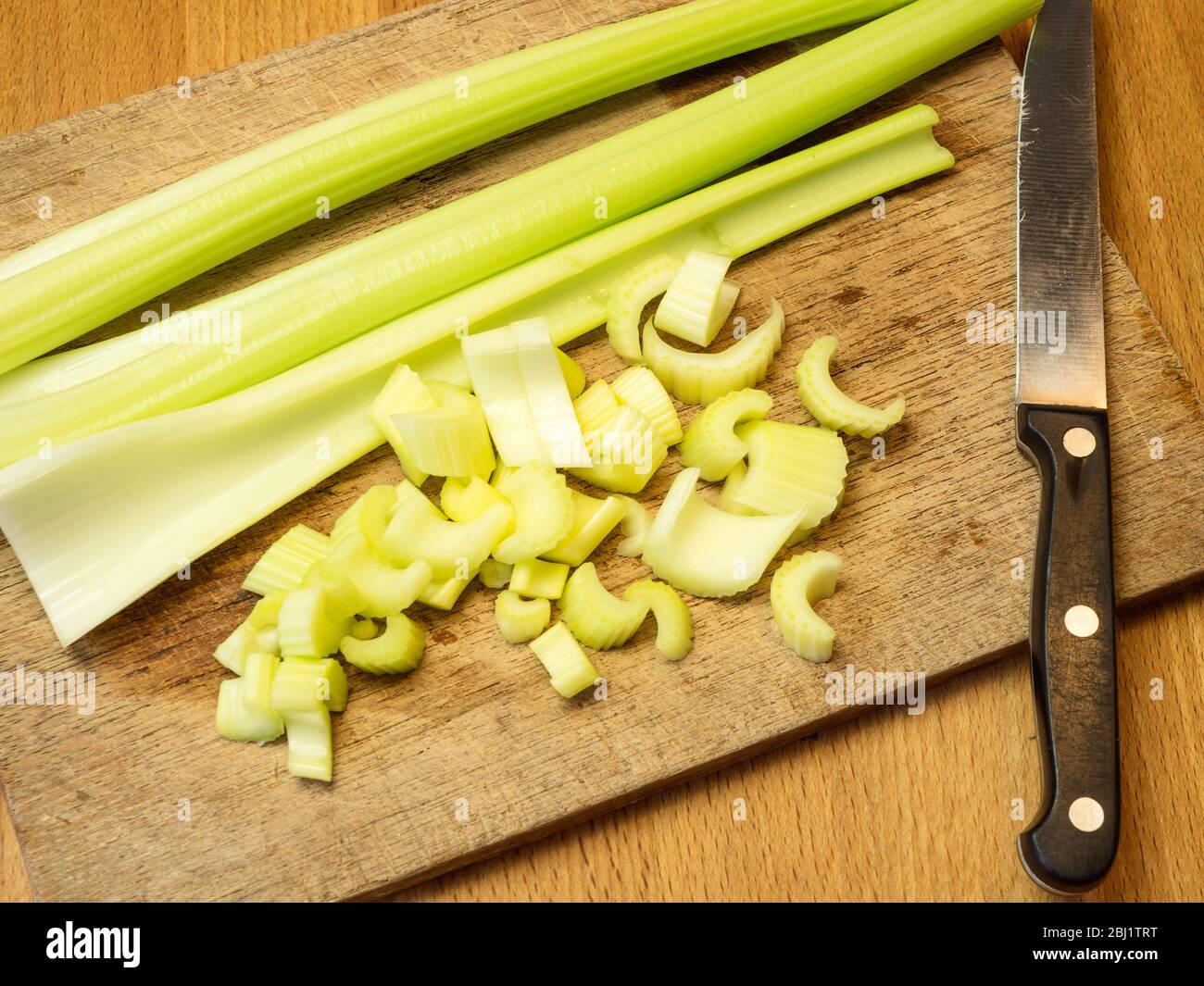 Chopping celery on a wooden chopping board on a kitchen table Stock Photo