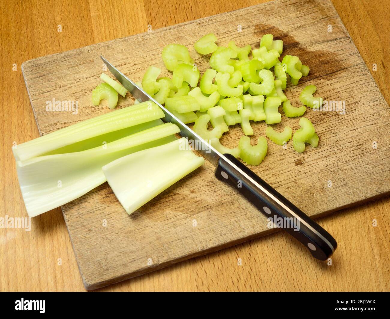 Chopping celery on a wooden chopping board on a kitchen table Stock Photo