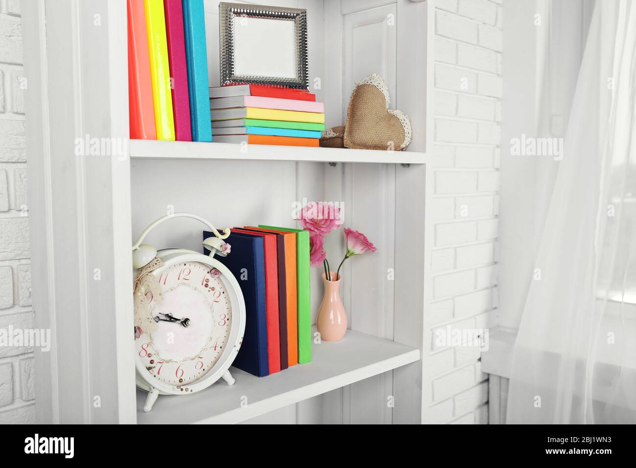 Books and decor on shelves in cupboard Stock Photo - Alamy