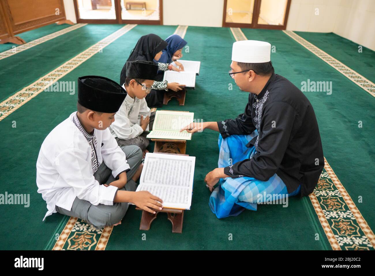 teacher is teaching muslim kid how to read holy quran in the mosque Stock Photo