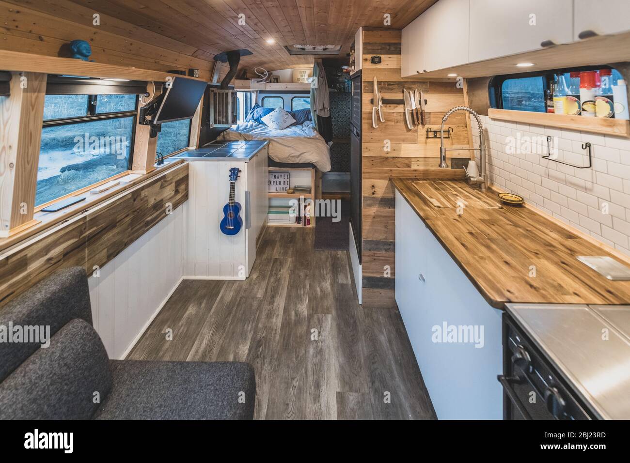 Interior of a campervan with a kitchen area in the foreground and sleeping area in the background. Stock Photo