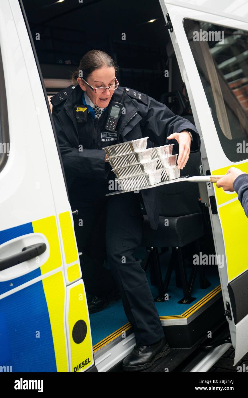 Food and drink is passed into a police van, at a free drive-through for the emergency services at The Berkeley Hotel as the UK continues in lockdown to help curb the spread of the coronavirus. Stock Photo